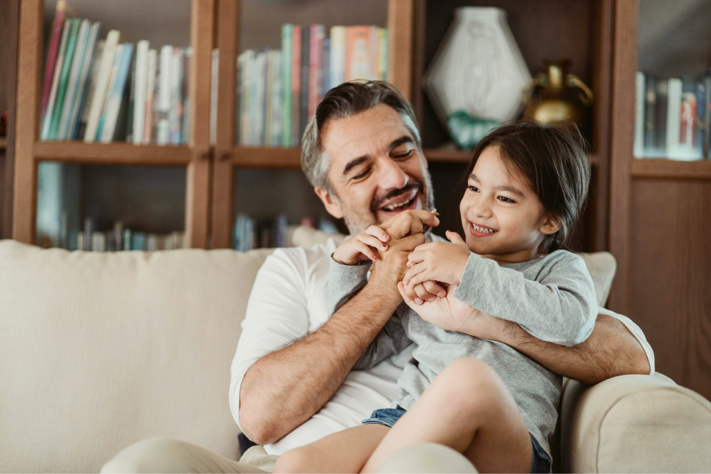 Adult and child smiling together while reading at home